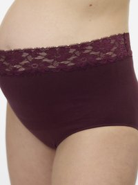 Κοντινές λήψεις ενός ατόμου που φορά βουργουνδί εσώρουχα εγκυμοσύνης με ζώνη από λουλουδάτη δαντέλα, δείχνοντας μια εγκυμονουσα κοιλιά από το πλάι.