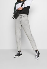 Grå högmidjade jeans med raka ben, mjuk denimtextur och en subtil blekt finish, i kombination med klassiska svarta högsko sneakers.