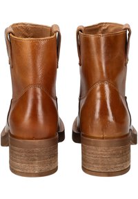 Bottines en cuir marron avec une texture lisse, bout rond et talon empilé. Comprend des languettes sur les côtés pour un enfilage facile.
