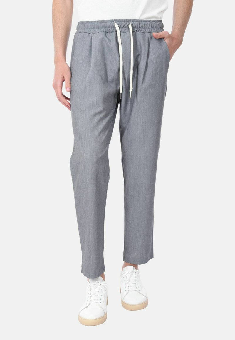 Pantaloni grigi leggeri con vita elasticizzata e cordoncino, caratterizzati da una vestibilità rilassata e una texture morbida. Abbinati a sneaker bianche.