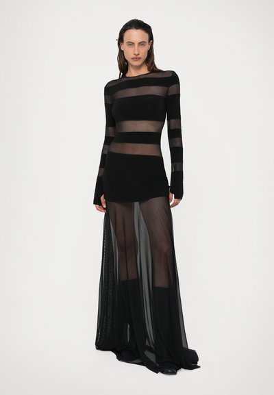 Črna obleka z dolgimi rokavi in prozornimi vodoravnimi črtami. Ima oprijet bodice in tekoč, plasteh obrezan krilo. Narejena je iz lahkotnega materiala.