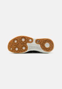 Shoe sole with a white midsole and gum rubber outsole featuring circular traction patterns and textured surface. Black accents along the sides.