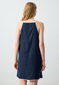 Abito senza maniche blu navy con bordi bianchi, forma A-line, tessuto morbido e zip posteriore. Design semplice con vestibilità comoda.