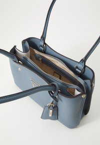 Borsa a tracolla in pelle blu texture, con doppi manici, hardware dorato, due scomparti con zip e un'etichetta charm staccabile.