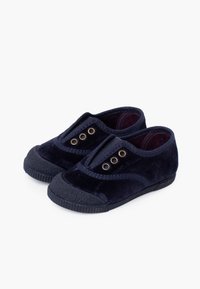 Zapatos tipo slip-on de terciopelo azul marino con punteras de goma y ojales. El diseño presenta una textura suave y una forma minimalista y redondeada.