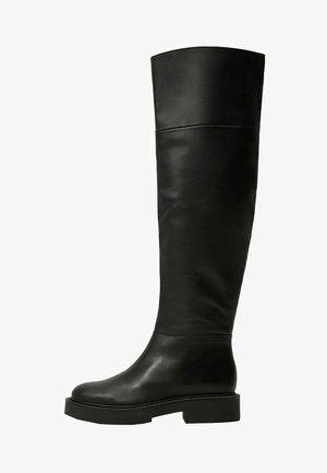 Botas negras hasta la rodilla, hechas de cuero suave, con punta redondeada, suela gruesa y un detalle de costura mínimo.