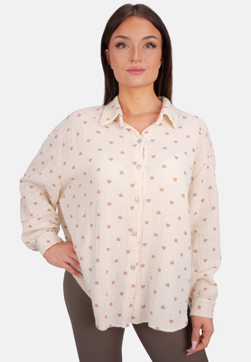 Cremfarbendes Hemd mit Knopfleiste, gefertigt aus strukturiertem Stoff, mit einem Herzmuster. Es hat einen Kragen und lange Ärmel mit geknöpften Manschetten.
