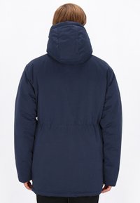 Jachetă din material albastru închis, căptușită, cu o glugă mare, talie strânsă și mâneci lungi. Textură netedă și design simplu.