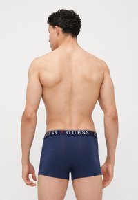 Boxeri navy din țesătură elastică, cu un croi ajustat și un brâu cu logo în contrast. Textură netedă și design minimalist.
