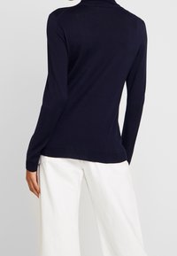 Maglione lavorato a maglia blu navy con maniche lunghe e scollatura a girocollo. Presenta una texture liscia e dettagli a costine sui polsini e sull'orlo.