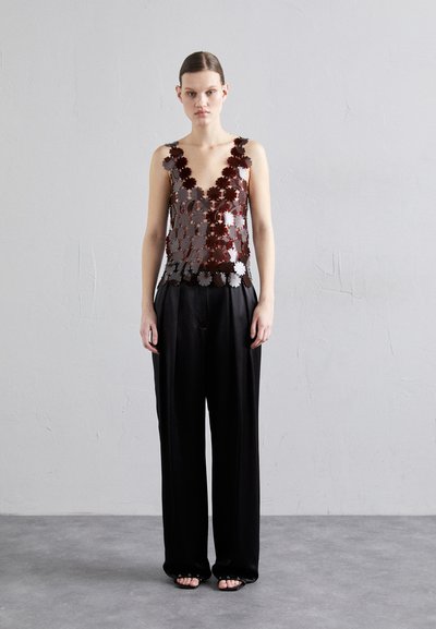 Metallic floral-patterned halter top in shades of red and silver, paired with loose black trousers, creating a layered texture effect.