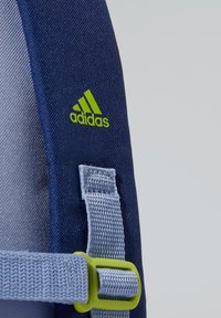 Mochila de tela navy con un logo verde de Adidas, correas grises con un cierre de color verde lima y superficie texturizada para mayor durabilidad.