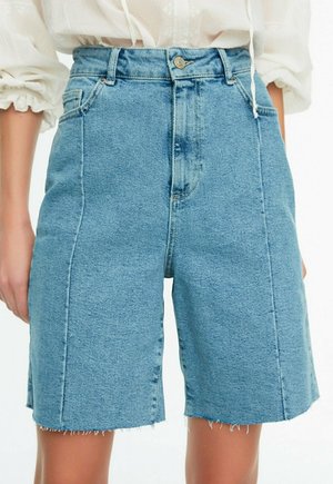Hoch taillierte, hellblaue Denim-Bermudashorts mit vorderem Knopf und Reißverschluss, seitlichen Taschen und rohen Saumkanten, getragen mit einem weißen Top.
