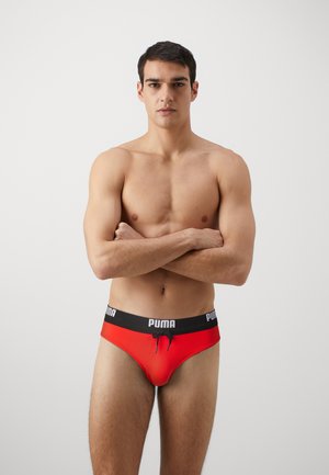 Røde boksershorts med sort taljebånd, der har PUMA-logoet. Stoffet ser glat ud med en tætsiddende pasform og en snøredetalje foran.