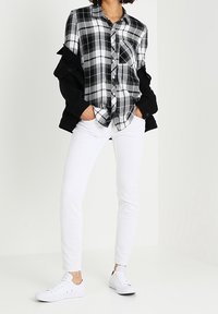 Black and white plaid button-up shirt with a front pocket, paired with white slim-fit pants and white sneakers.