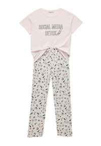 Camiseta rosa claro con "DESINTOXICACIÓN DE REDES SOCIALES" impreso en negro, combinada con pantalones de pijama blancos que presentan un patrón divertido de varios íconos.