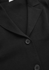 Sort cardigan med en tekstureret strikket design, reverskrave og to sorte knapper foran. Enkel og alsidig stil.