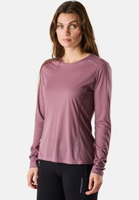 Vaaleanliila pitkähihainen urheilupaita, jossa on tekstuuri kangas, pyöreä pääntie ja sivusaumat istuvaa ilmettä varten.