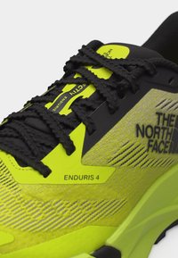 Φωτεινό κίτρινο και μαύρο παπούτσι για τρέξιμο The North Face Enduris 4 με μαύρα κορδόνια και λεπτομέρειες από πλεκτό ύφασμα.