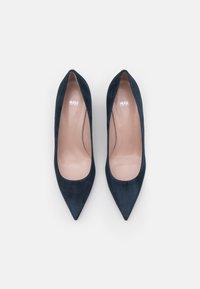 Escarpins en daim bleu marine à talons hauts avec un bout pointu et une doublure intérieure lisse. Présentent un petit logo imprimé sur la semelle intérieure.