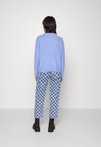 Ljusblå stickad tröja med ribbad textur, kombinerad med blå och vita rutig byxor och svarta klumpiga klackboots.