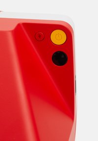 Red electronic device featuring a textured surface, with yellow power button, lightning icon, and a circular black button. Angular design accents.