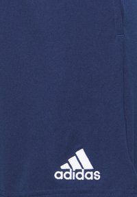 Tissu bleu marine avec logo Adidas blanc brodé près du bord inférieur droit.
