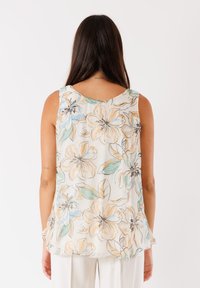 Blusa senza maniche floreale realizzata in un tessuto morbido e leggero, con fiori beige, blu e verdi, e un collo arrotondato.
