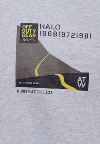 Grått tyg med ett grafiskt tryck i gult. Texten inkluderar "OFF DUTY GEAR," "HALO 196819," och "ALL TERRAIN WEAR." Enkelt mönster.
