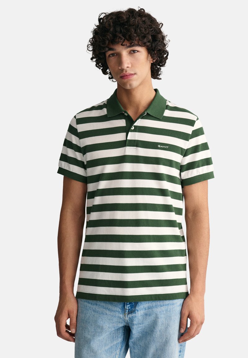 Polo de rayas verdes y blancas hecho de algodón, con cuello y detalle del logotipo en el lado izquierdo del pecho. Corte clásico y mangas cortas.