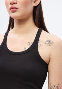 Μαύρο ριμπ αμάνικο τοπ με στρογγυλό ντεκολτέ και στενές τιράντες. Διαθέτει κεντημένο λογότυπο και εμφανή τατουάζ με λουλούδια και μάτι στον ώμο.