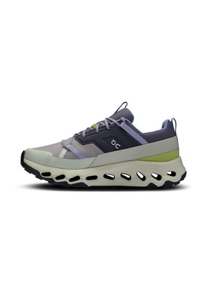 Chaussure de sport basse avec des accents gris, noirs et verts, tige en mesh respirant, fermeture à lacets et semelle épaisse avec des trous de ventilation découpés.