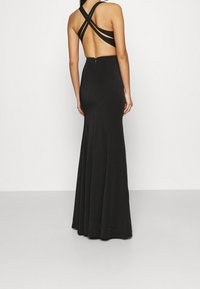 Černé, přiléhavé večerní šaty s otevřeným zadním dílem, křížovými ramínky a lehkým rozšířením na spodním okraji. Vyrobené z hladkého, elastického materiálu.