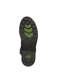 Semelle en caoutchouc noir avec un profil de texture. Présente des accents verts dans un motif en zigzag. Les parois latérales ont une finition lisse et un logo de marque visible.