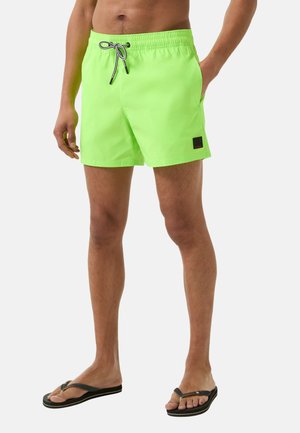 Neon groene zwembroek met een elastische tailleband en een zwart aantrekkoord. Bevat zijzakken en een klein zwart logo-patch op de zoom.