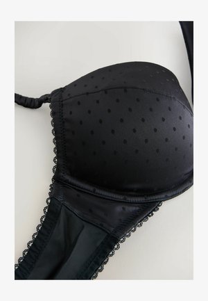 Fekete párnázott melltartó pöttyös mintával, csipkés szegéllyel a szélein és vékony állítható pántokkal, sima, selyemszerű textúrával.