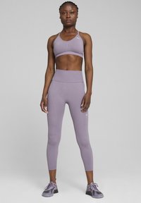 Violet sportinė liemenėlė ir leggingai, pagaminti iš tamprios medžiagos, sukurti su prigludusia siluetu. Papuošti logotipu viršuje ir glotnia tekstūra.