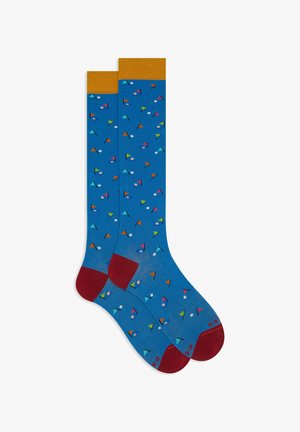 Blue socks with colorful geometric patterns, yellow ribbed cuff, red heel and toe, made of soft material. Pattern includes triangles and circles.