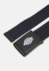 Sötétkék, szövött öv fekete fém csattal. A csattón egy kör alakú logó található a "Dickies" felirattal. A textúra bordázott.