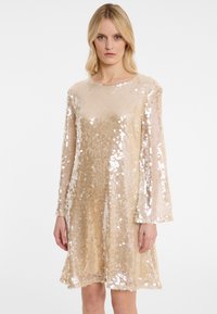 Robe à manches longues en tissu transparent doré, ornée de sequins, avec un col rond et une silhouette ample.