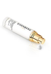 Bouteille cylindrique blanche avec des accents dorés, étiquetée "Eisenberg Paris." Une petite quantité de crème est dispensée par la pompe.