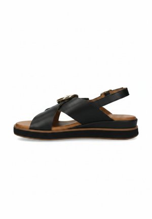 Sandale slingback en cuir noir avec larges brides croisées, détail boucle dorée, semelle intérieure marron rembourrée et semelle épaisse noire avec bordure marron.