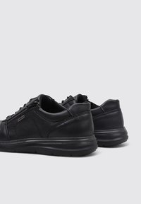 Chaussures en cuir noir avec un design arrondi, des lacets à l'avant et une fermeture éclair latérale. Des accents en cuir texturé et des semelles en caoutchouc offrent soutien et adhérence.