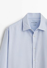 Lichtblauw longsleeve shirt met witte verticale strepen. Voorzien van een klassieke kraag en knoopsluiting, gemaakt van zachte stof.