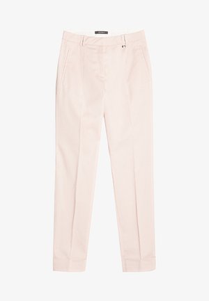 Zwarte losse top met korte mouwen, gecombineerd met lichtroze tapered pants en witte strapsandalen, tegen een effen achtergrond.