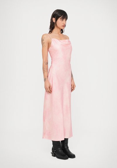 Ružové, bezrukávové maxi šaty s okrúhlym výstrihom, hladká textúra a voľný strih, v kombinácii s čiernymi členkovými čižmami s masívnym podpätkom.