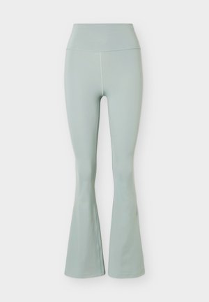 Svetlozelené legíny s vysokým pásom a rozšíreným strihom na nohaviciach, hladkým predným dielom bez švov a jemnou textúrou látky na jednofarebnom pozadí.