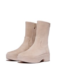 Beige suede enkellaarsjes met een gladde textuur, ronde neus en een robuuste platformzool. Voorzien van een zijrits voor eenvoudig aan- en uittrekken.