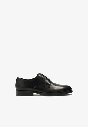 Scarpe in pelle nera con lacci, dalla superficie liscia, punta arrotondata e suola in gomma robusta. Presentano cuciture minime e linee pulite.