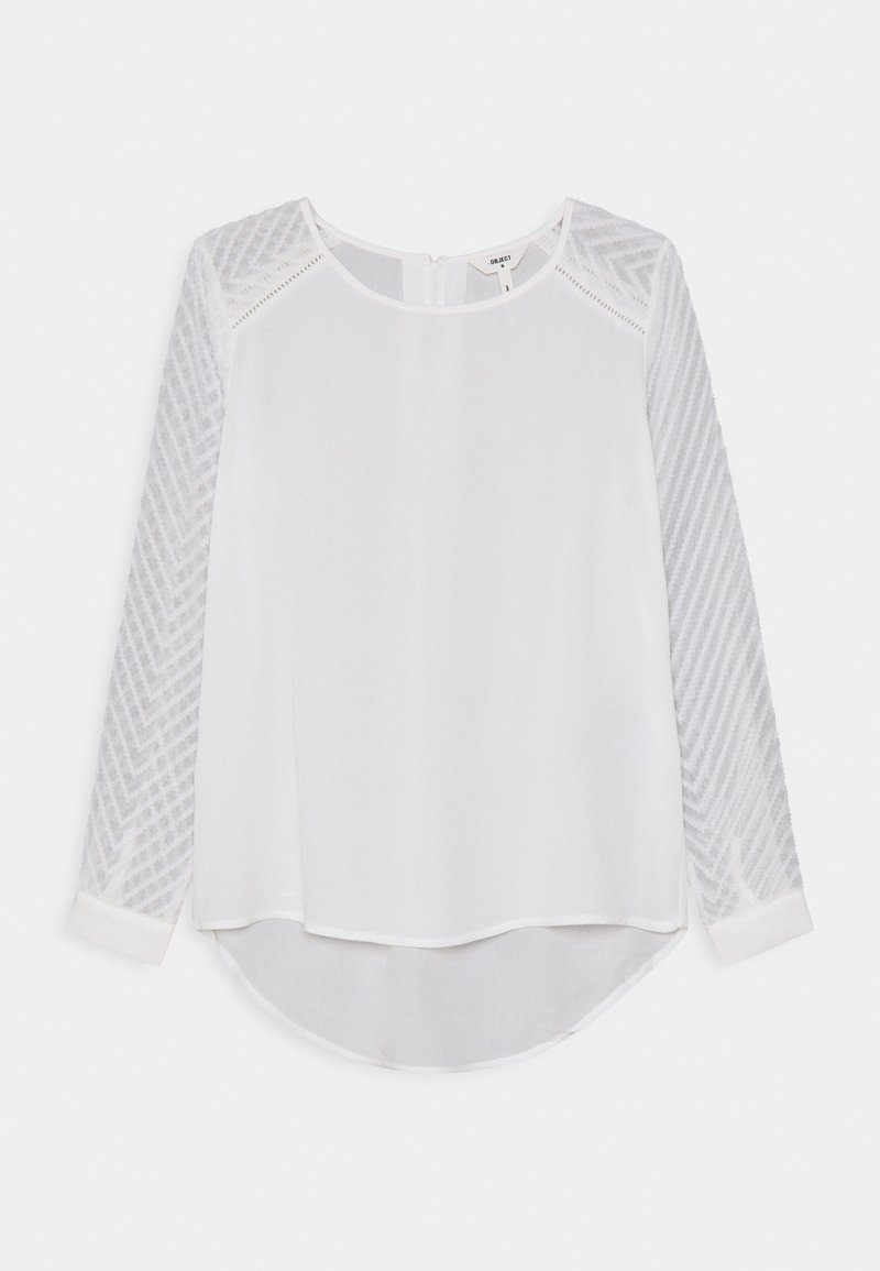 Hvid bluse med lange, teksturerede ærmer, der har et fiskebensmønster, rund halsudskæring og en let buet underkant.